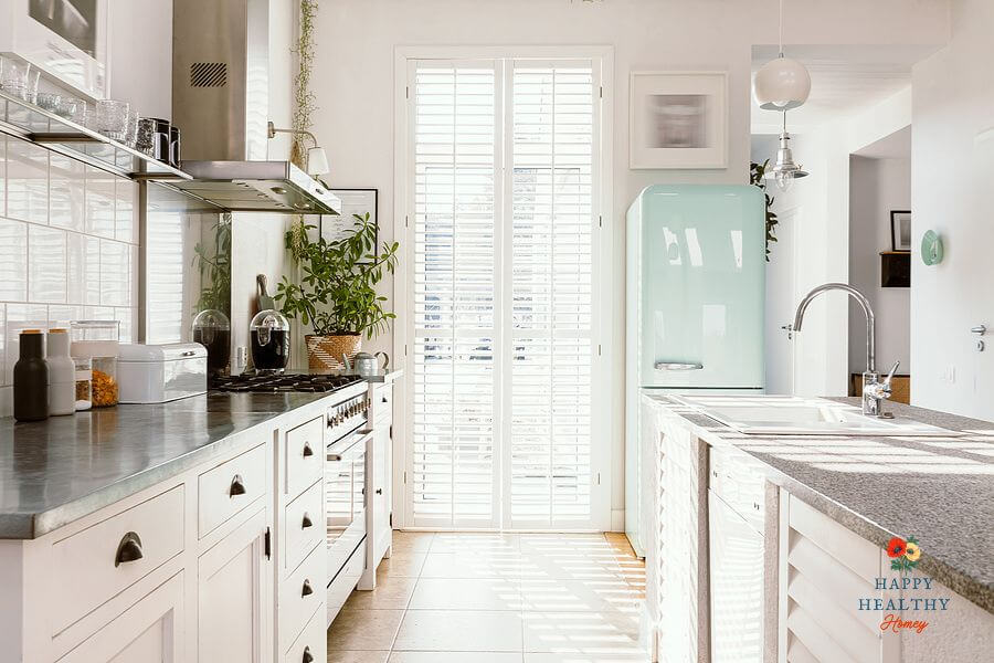 Sunny, modern kitchen with white cabinets and a mint green refrigerator, conveying cleanliness and organization ideal for gluten-free cooking.