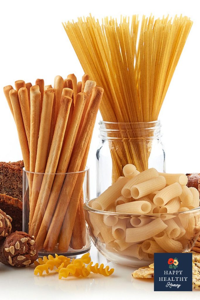 Assorted gluten-containing foods including spaghetti, rigatoni, breadsticks, and baked goods displayed in jars and bowls, illustrating sources of gluten.