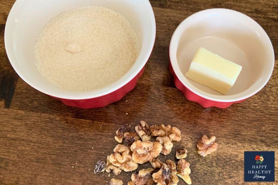 Simple ingredient shot for candied walnuts with sugar, butter, and a small pile of toasted walnuts.