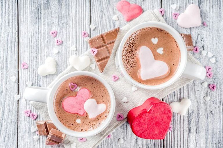 Two mugs of homemade hot cocoa with heart-shaped marshmallows and chocolate, perfect for Valentine’s Day.