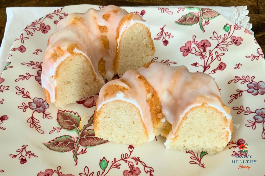 Gluten-free Meyer lemon mini bundt cakes with lemon glaze cut in half on a floral plate.