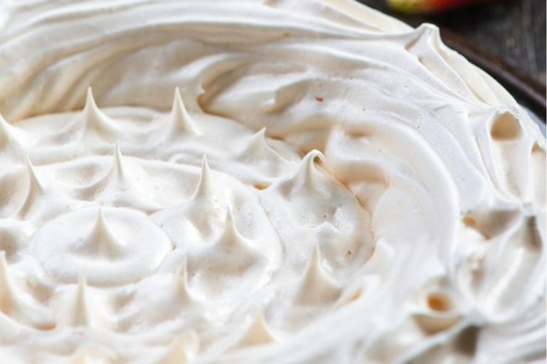 Close up view of a baked meringue pie crust with golden peaks.